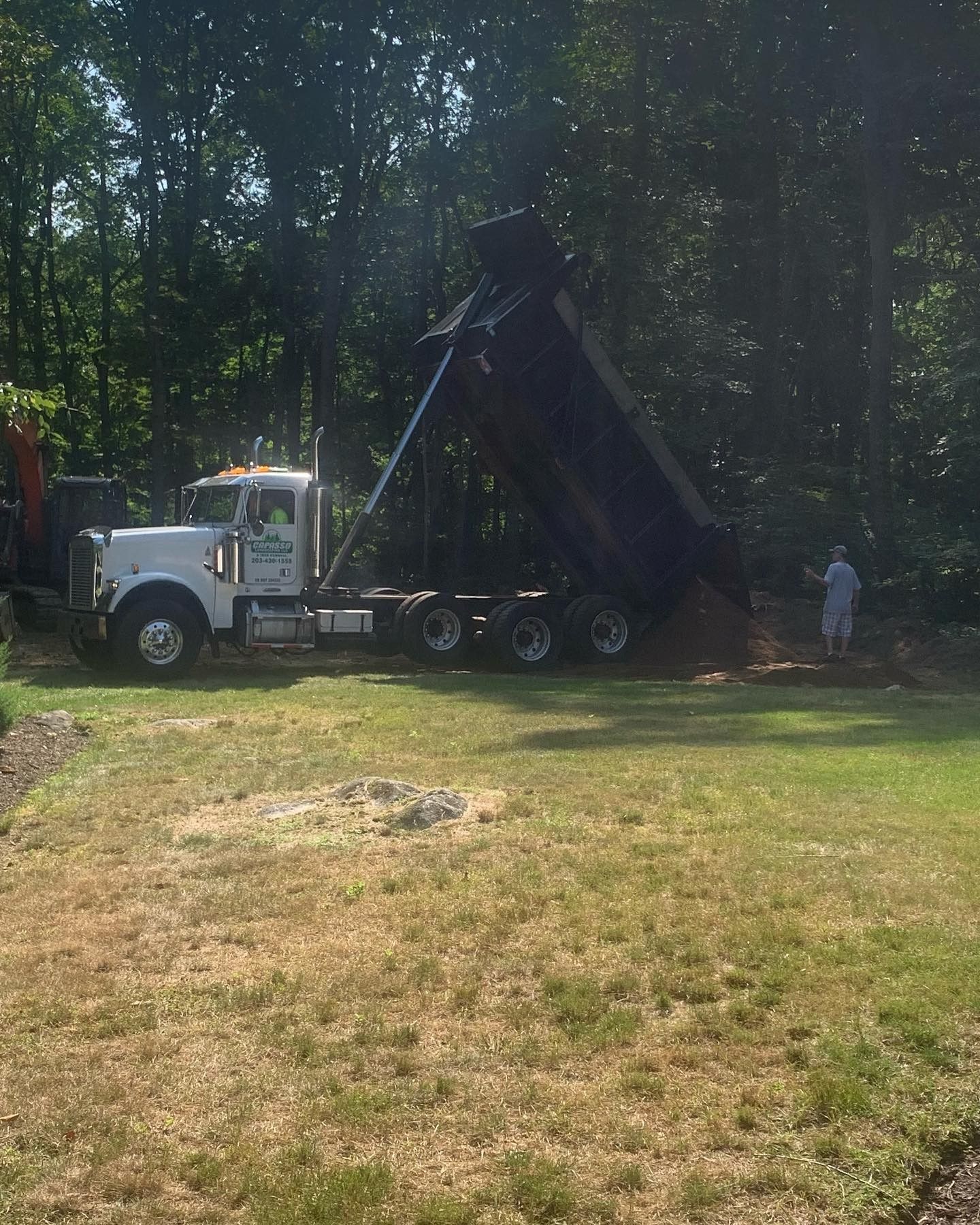 A dump truck is sitting on top of a lush green field.