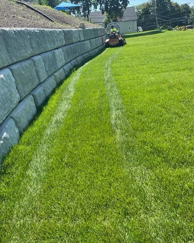 A metal planter filled with flowers is next to a building.