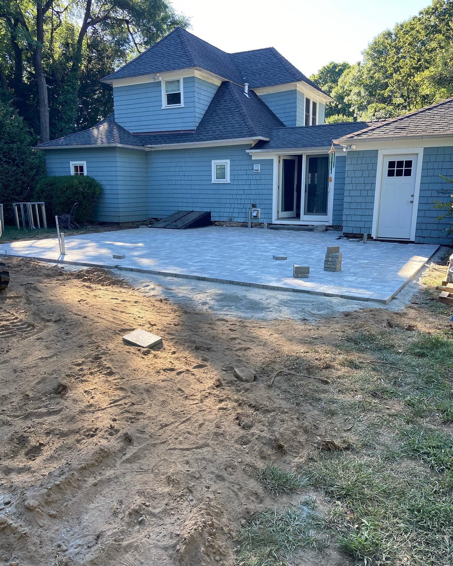 A blue house with a patio being built in front of it.