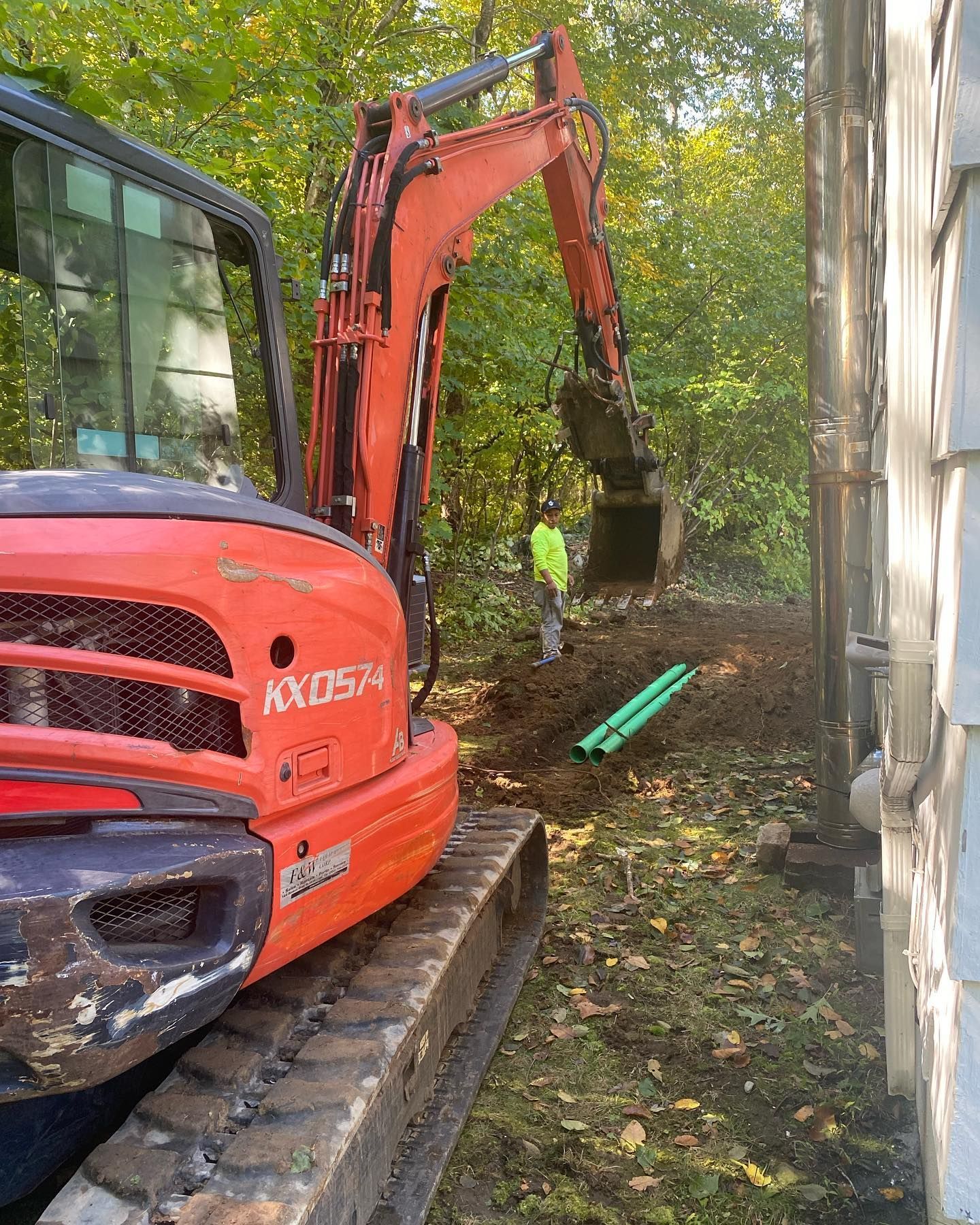 A man is standing next to a large orange excavator.