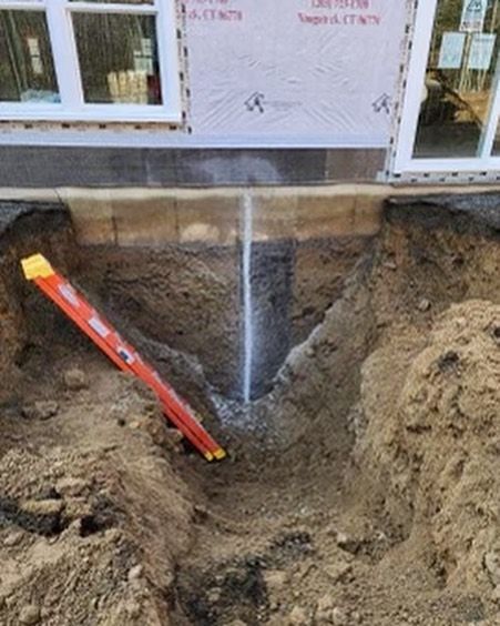 A red ladder is sitting in the dirt next to a window.