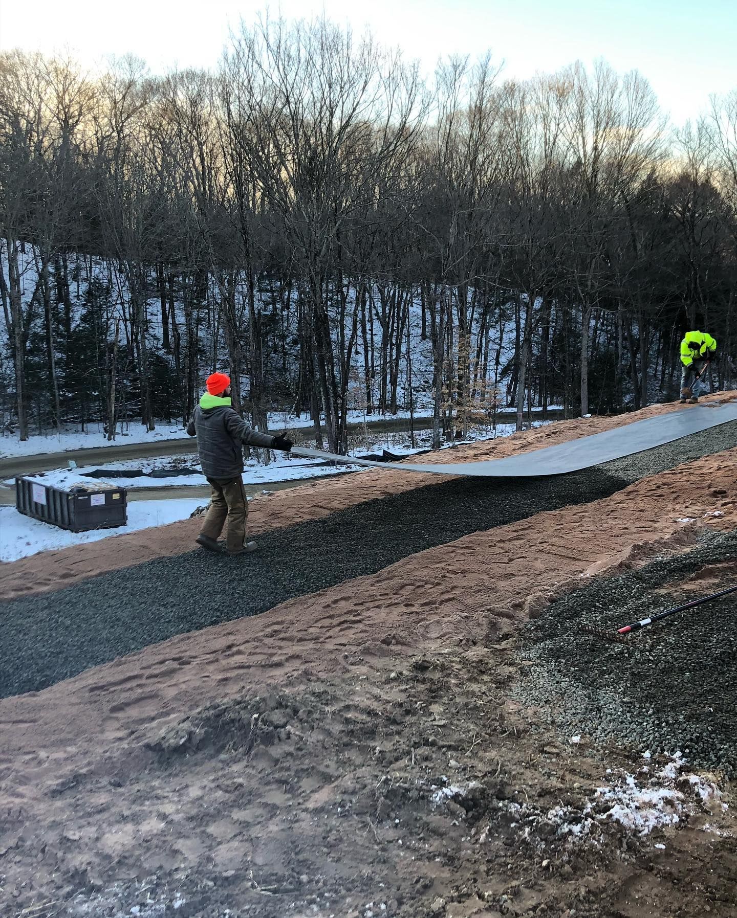 A man is laying down a covering on a path.