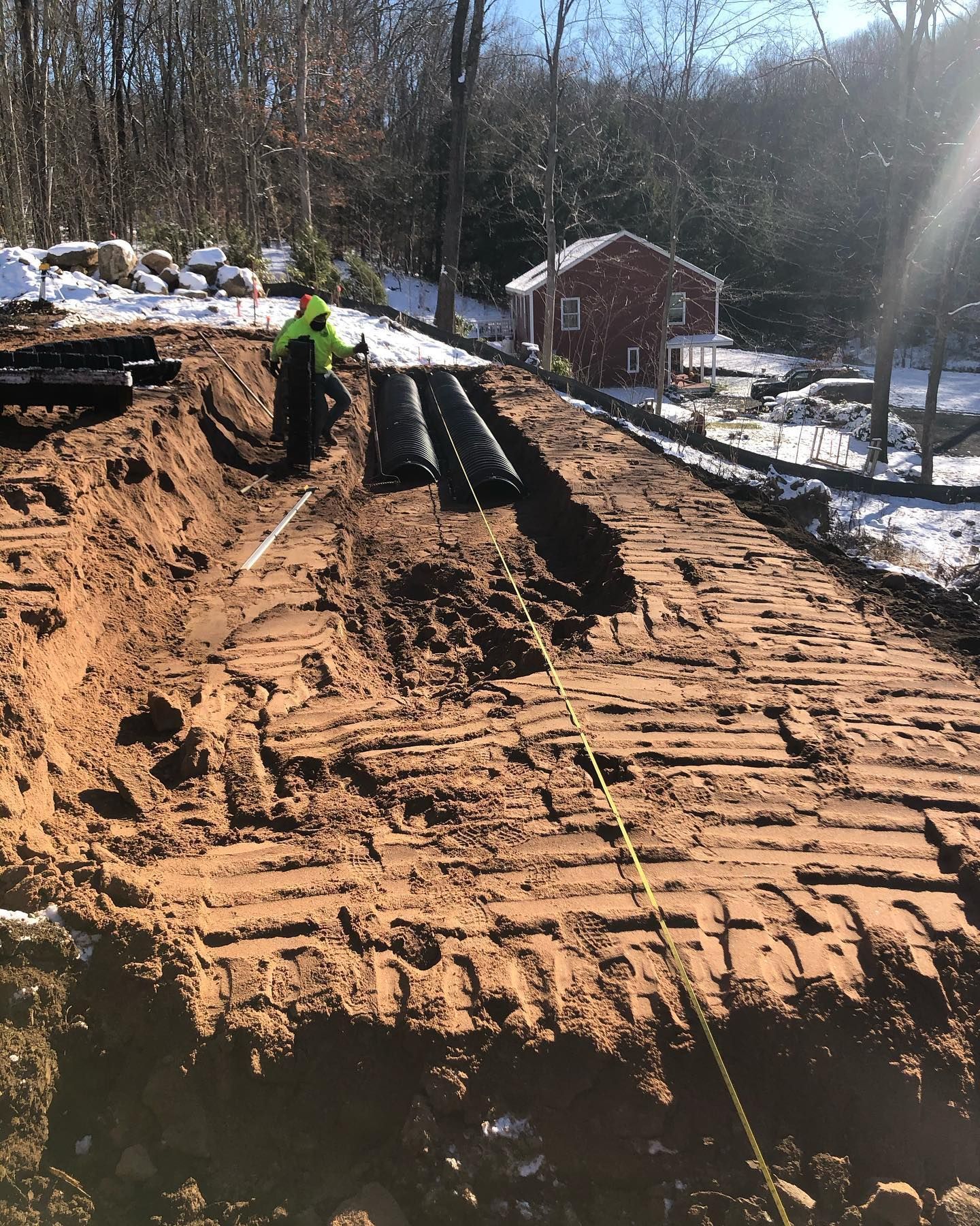 A man is digging a hole in the dirt in front of a house.
