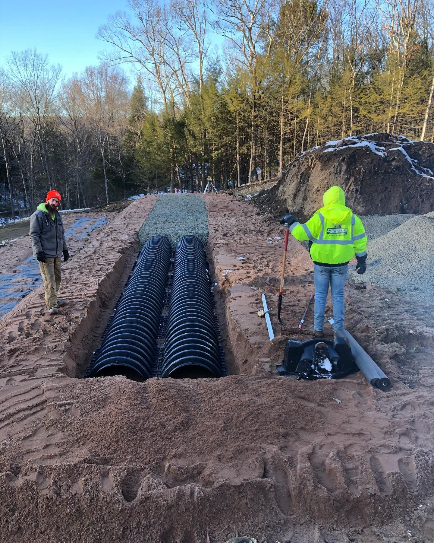 Two men are working on a pipe system in the dirt.