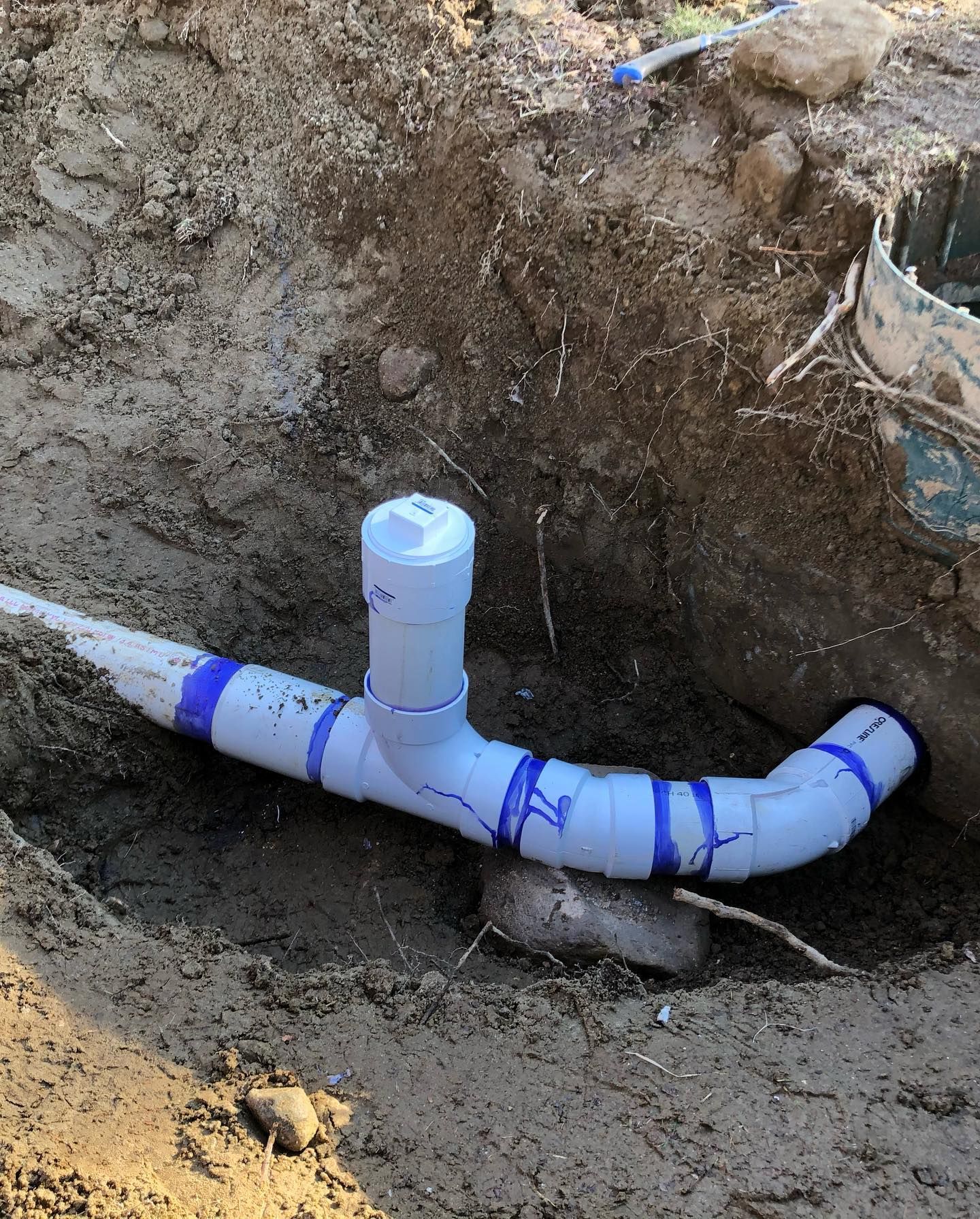 A white pipe is sitting in the dirt in a hole.
