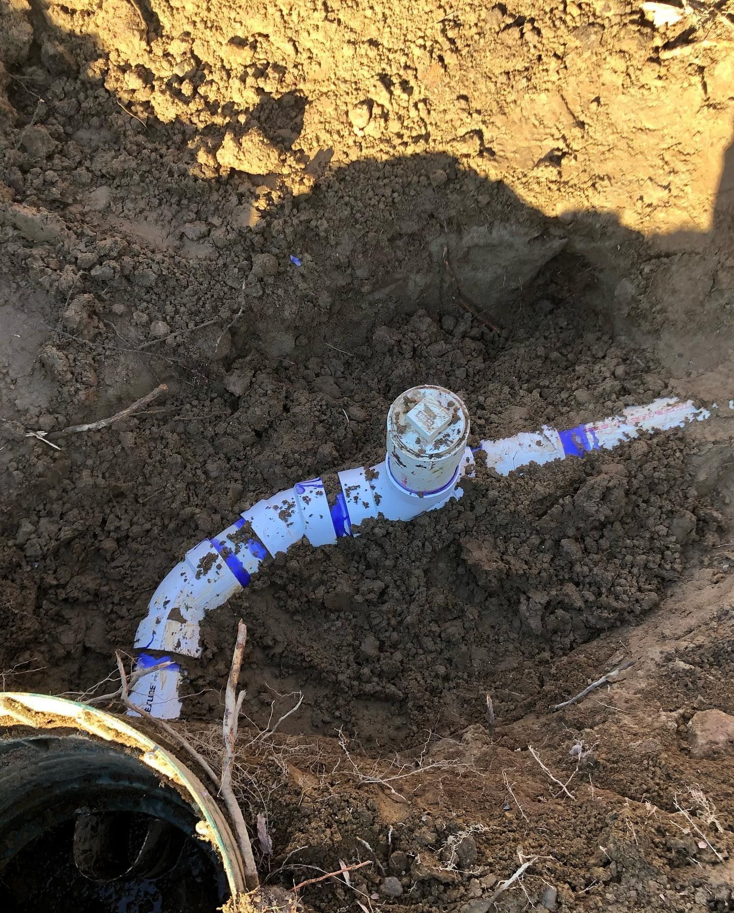 A hose is laying in the dirt next to a pipe.