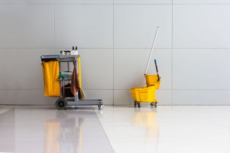 a yellow caution bucket sits next to a cleaning cart