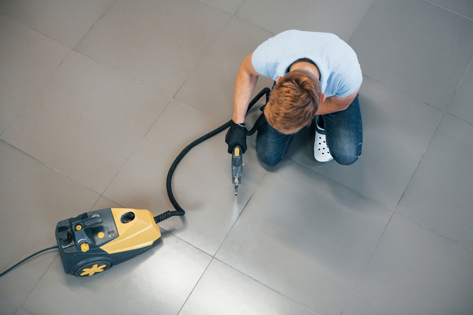 a man is kneeling on the floor using a vacuum cleaner .