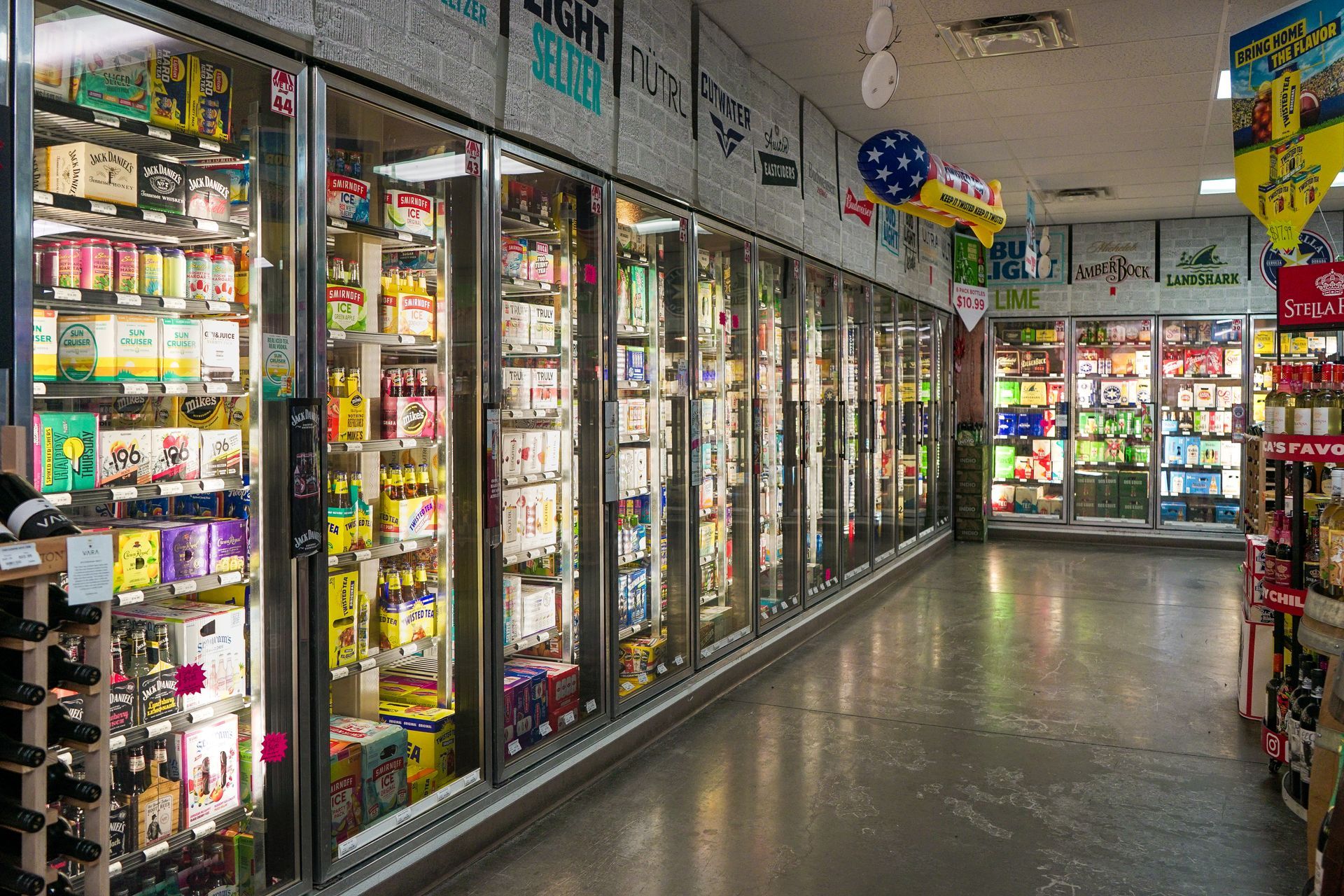 Rows of refrigerated beverage cases in a store, filled with various colorful products.