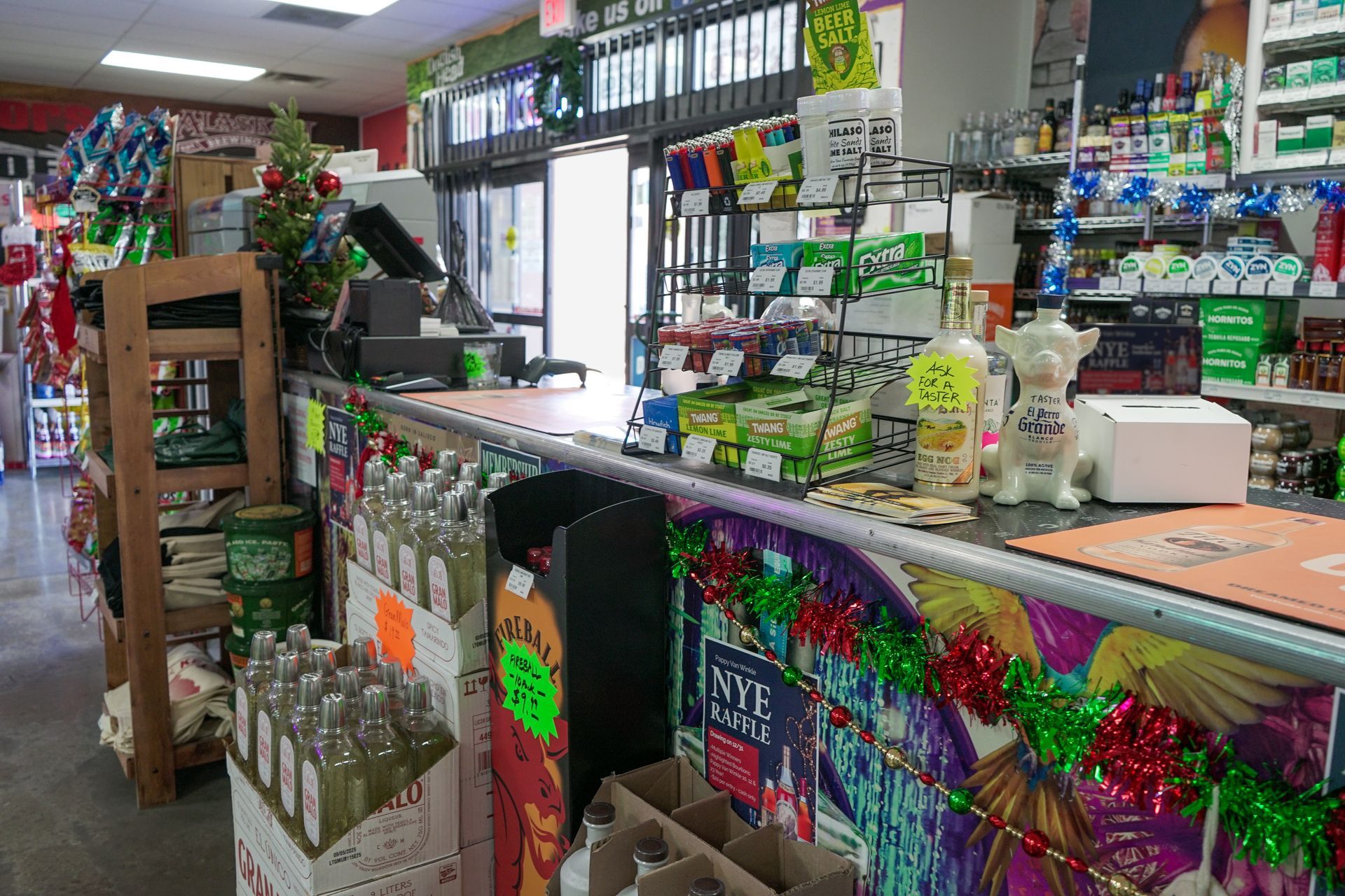 Interior of a store with a counter, merchandise, and an open doorway. Decorated for the holidays.