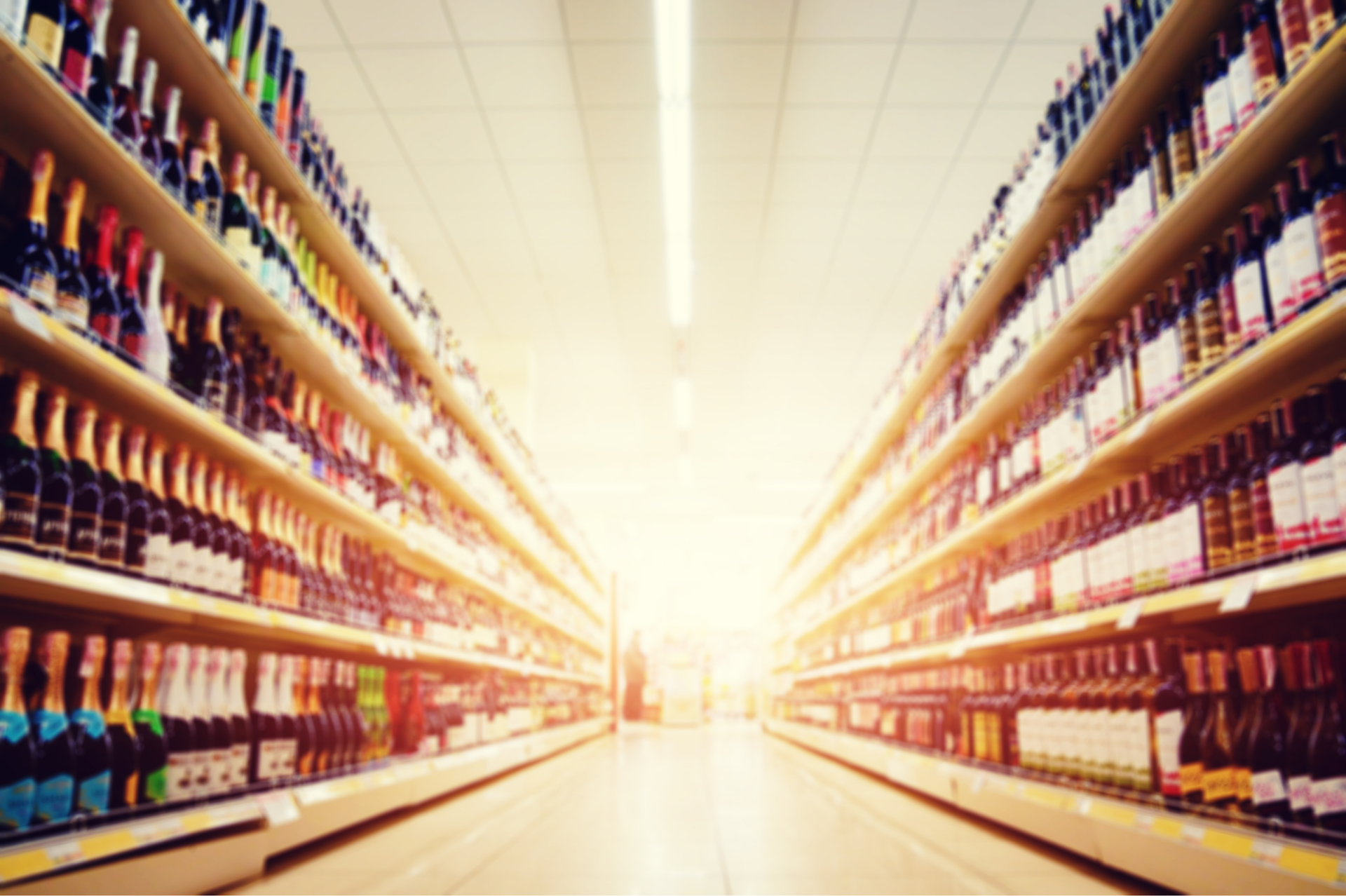 Three bottles of Korean soju, a menu, and a cup on a bar in a dimly lit setting.