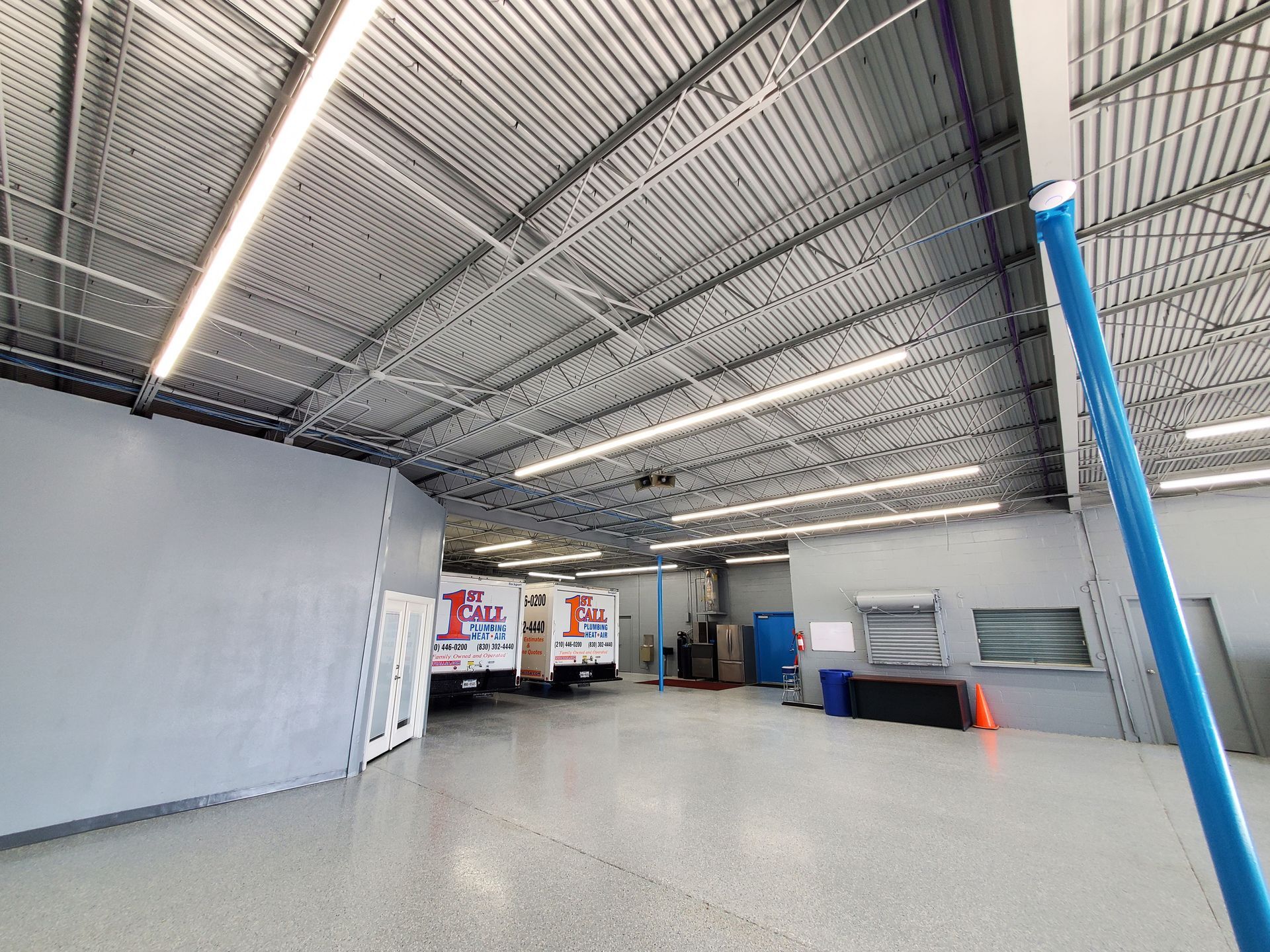 Interior of warehouse with trucks, gray walls, and metal ceiling.