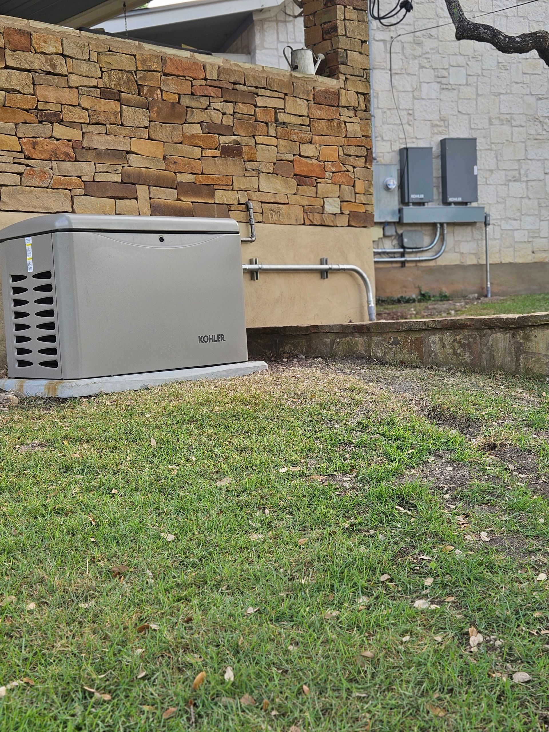 A generator and solar panel components sit outside a house with a stone wall.