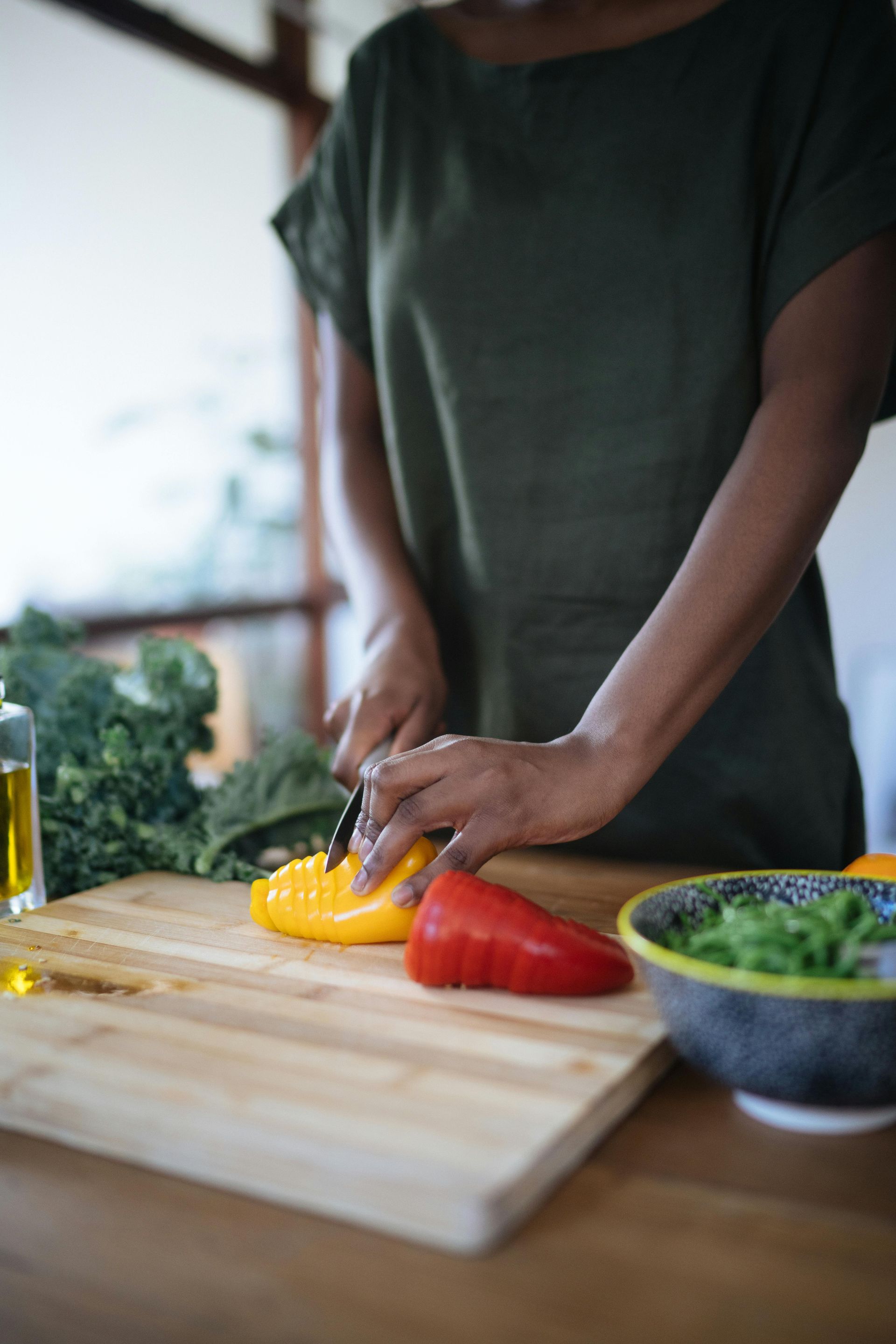 A woman is cutting vegetables on a cutting board.