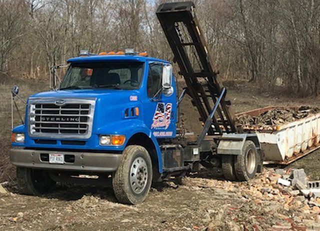 A blue dump truck is driving down a dirt road.