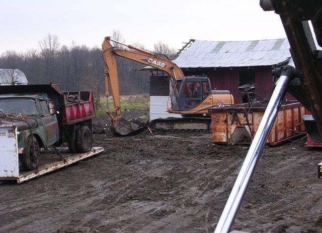 A case excavator is digging in the dirt next to a dump truck