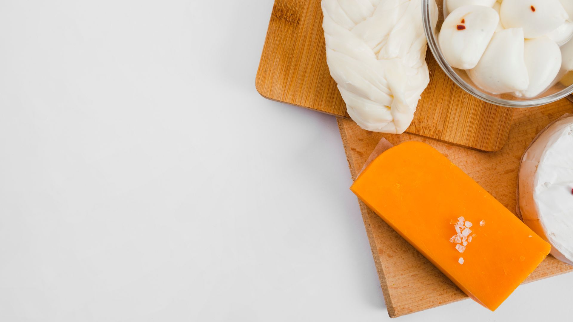 Cheese varieties on wooden boards: braided, orange block, and small balls.