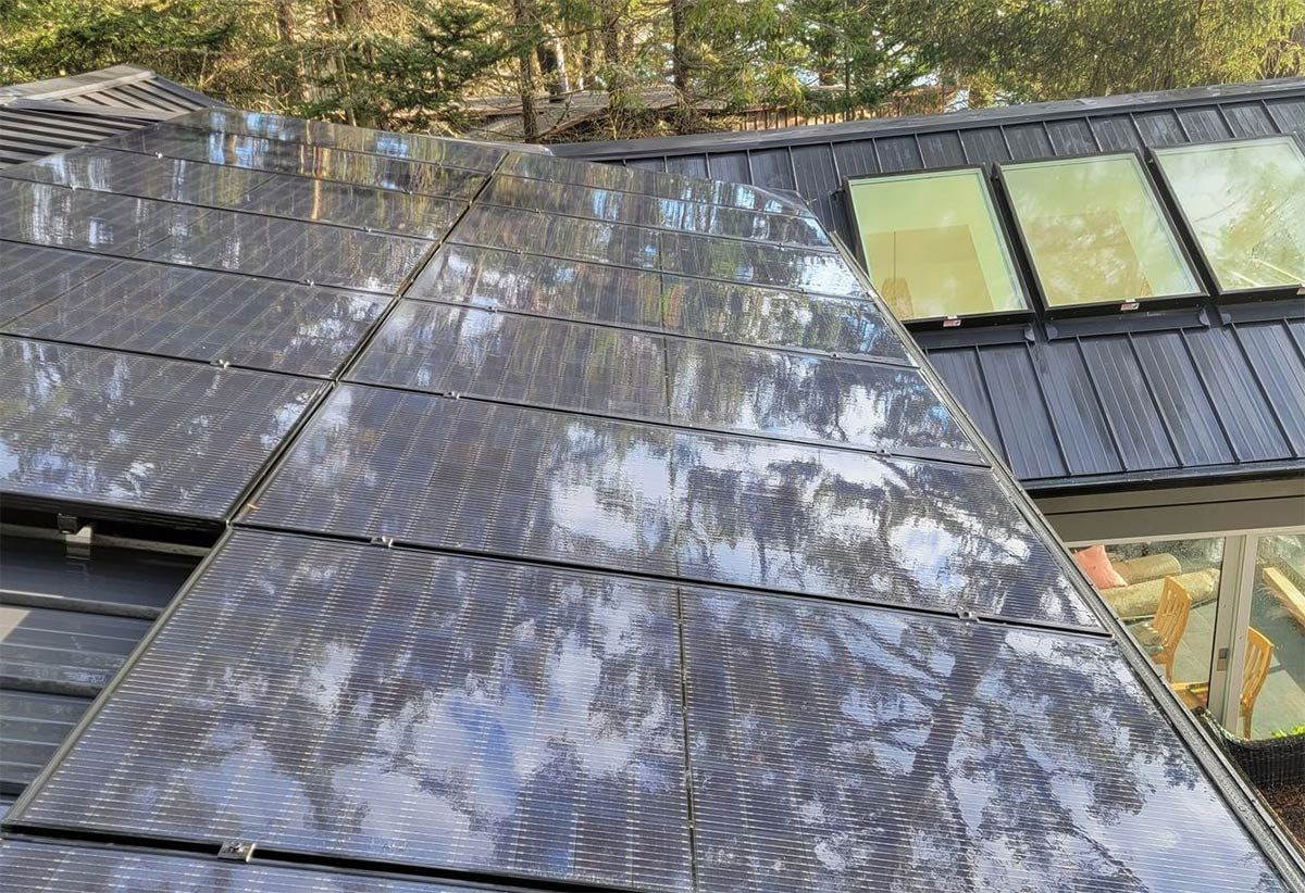 Freshly cleaned solar panels on a roof, reflecting the sky. Several panels are dark, others are yellow.