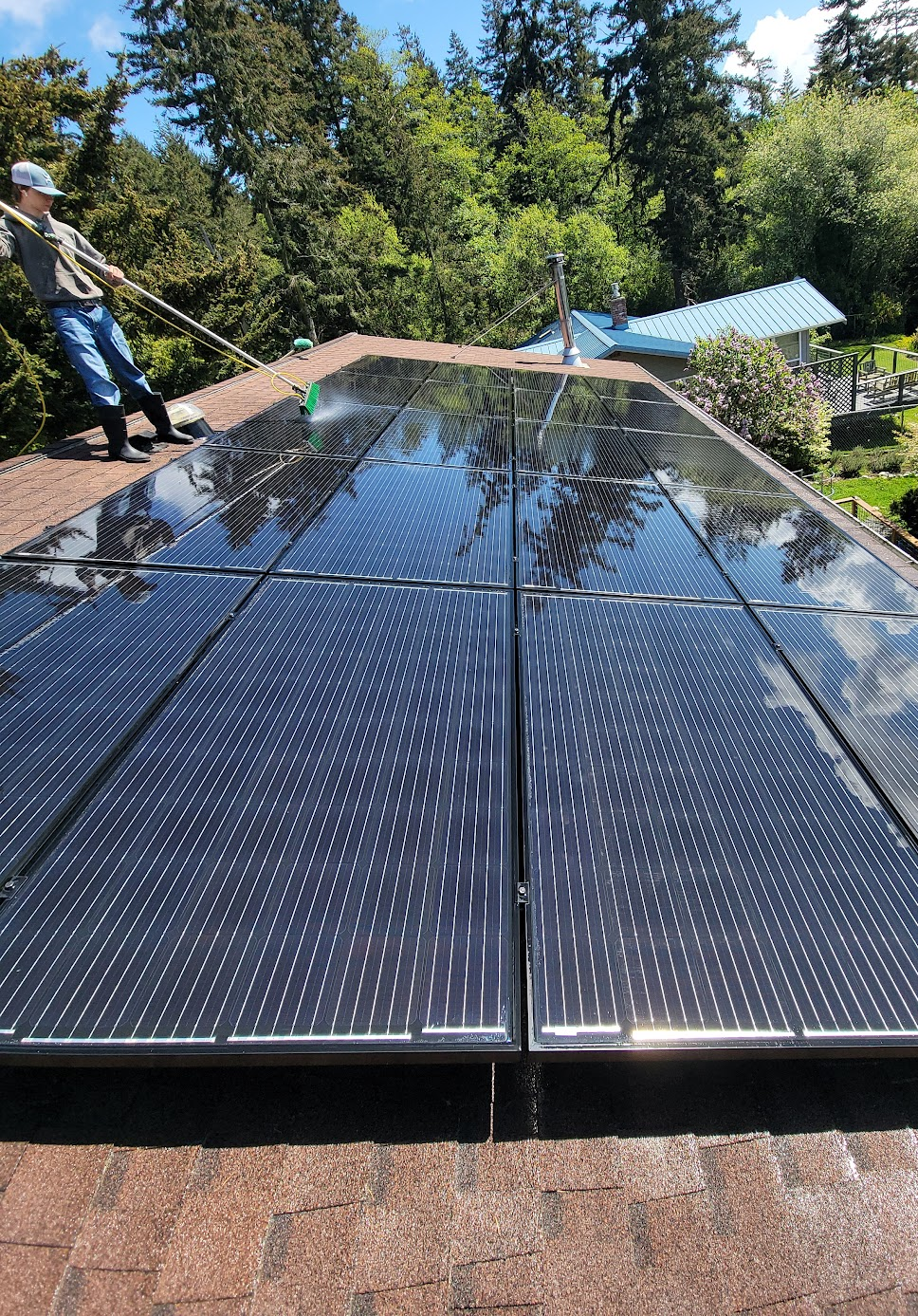 Solar panels installed on a rooftop; person securing equipment on a sunny day.