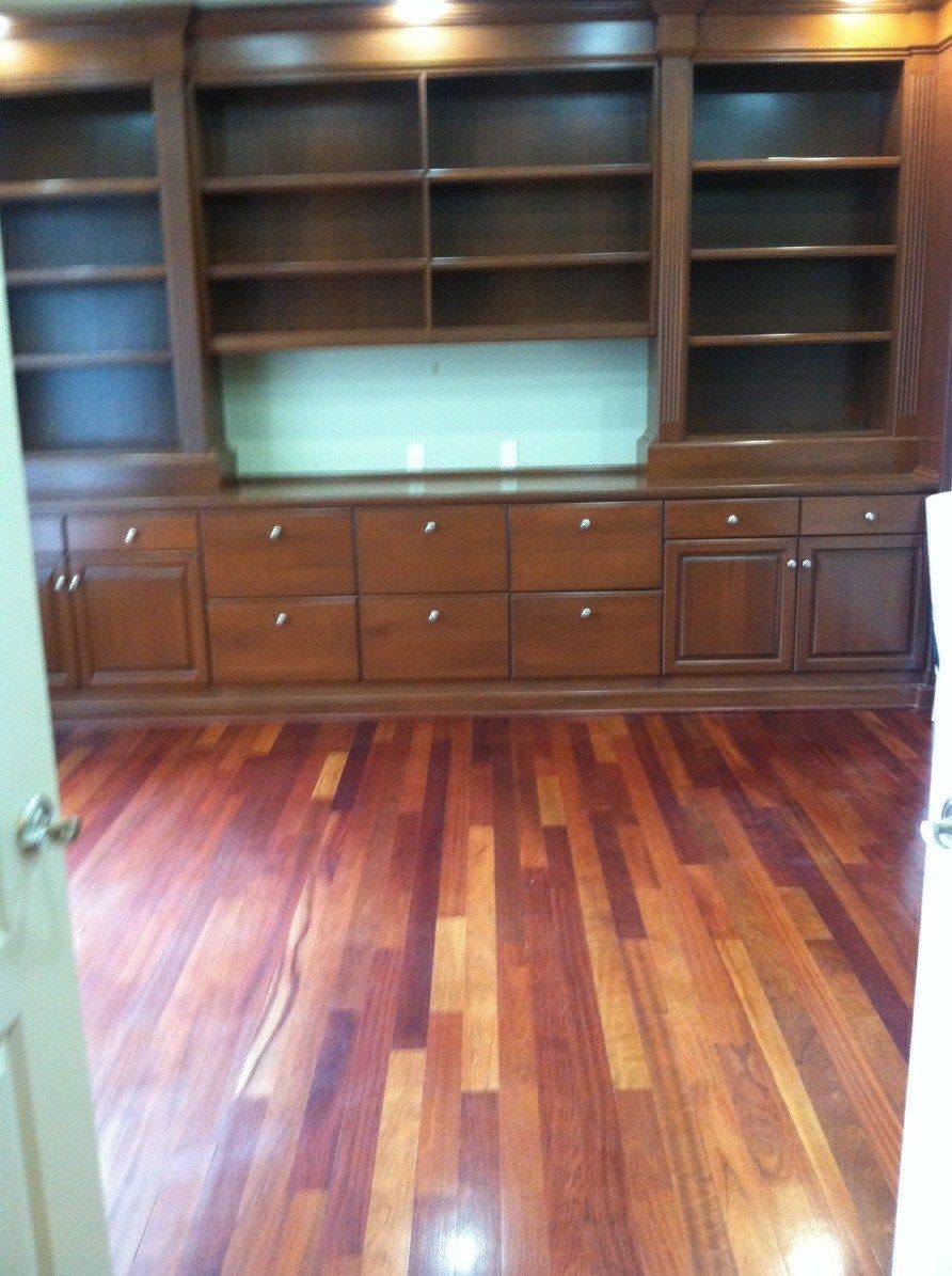 An empty room with hardwood floors and a bookcase