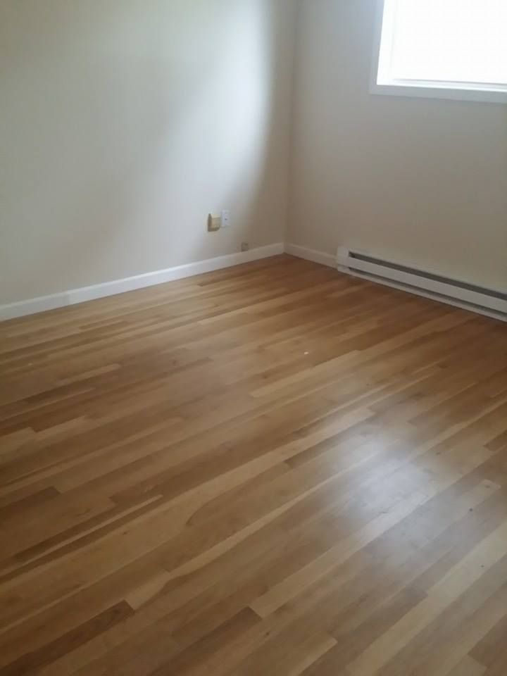 An empty room with hardwood floors and a window.