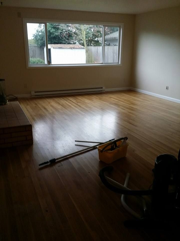 An empty living room with hardwood floors and a window.