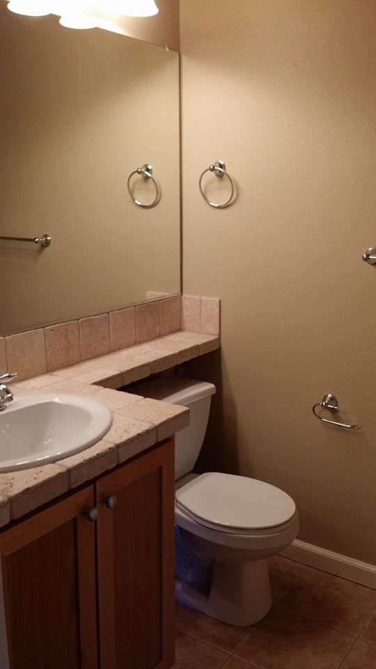 A bathroom with a toilet , sink and mirror.