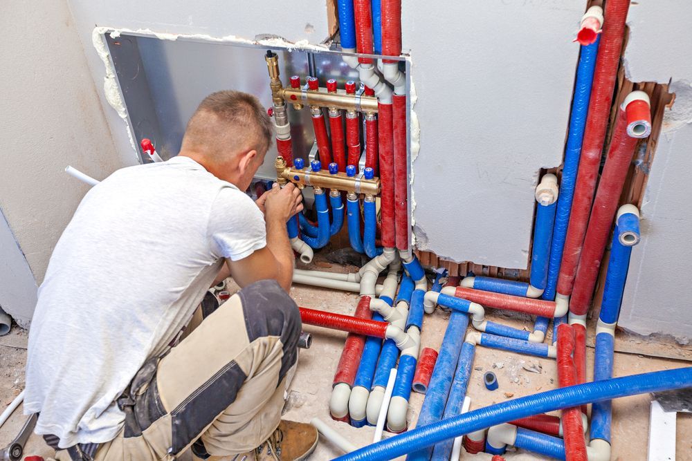 A Plumber is Working on a Pipe System in a Bathroom — Andergrove Plumbing & Drainage Pty Ltd In Bowen, QLD