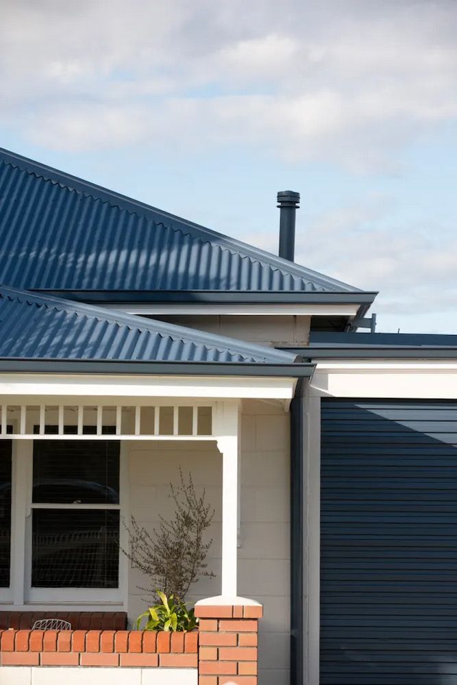 A House With a Blue Roof and a Black Garage Door — Andergrove Plumbing & Drainage Pty Ltd In Richmond, QLD