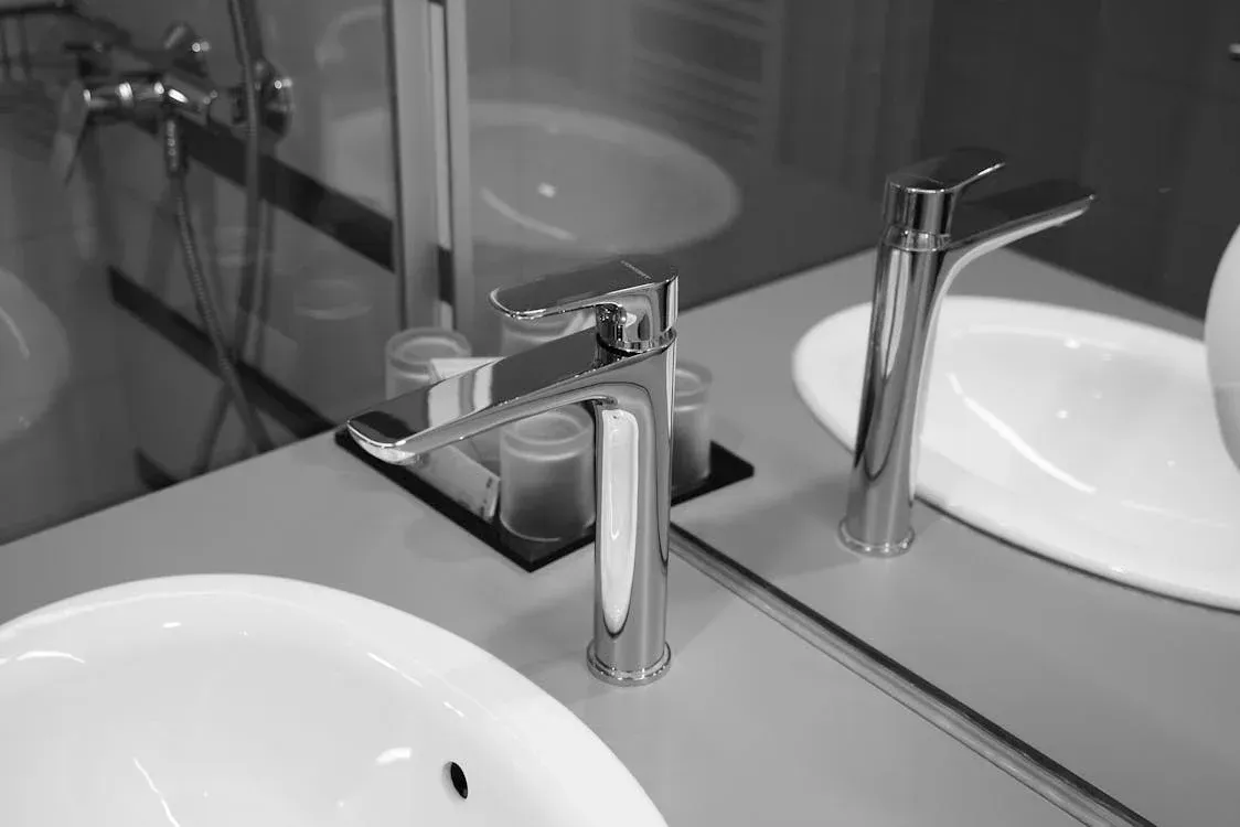 A Black And White Photo Of A Bathroom Sink And Mirror — Andergrove Plumbing & Drainage Pty Ltd in Richmond, QLD