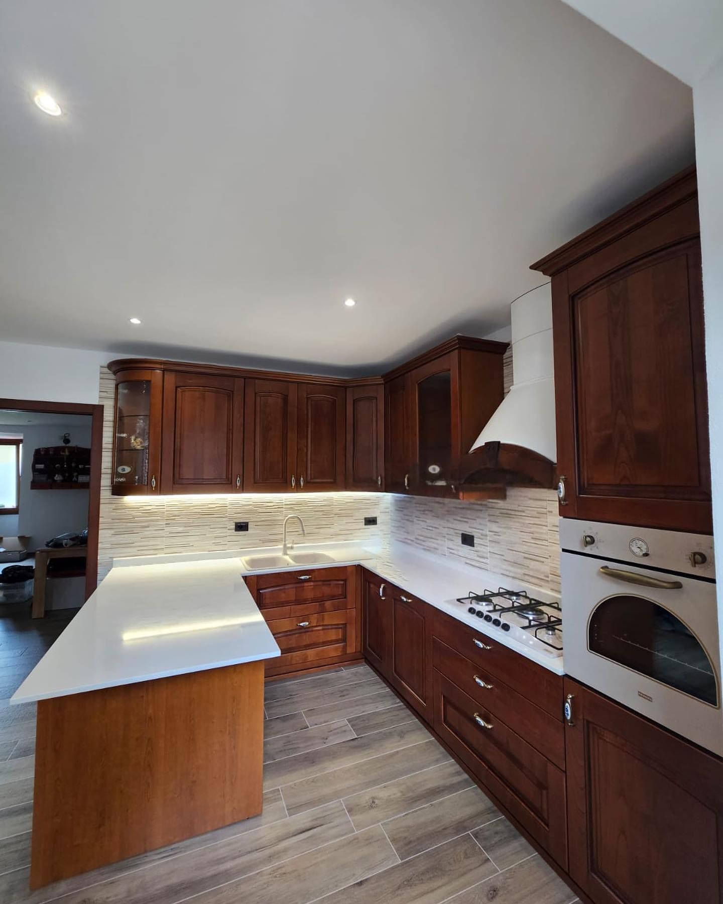 Una cucina con mobili in legno e un piano di lavoro bianco