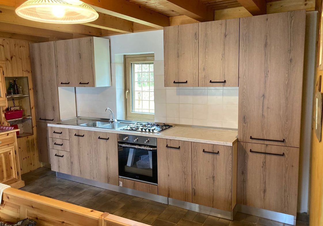 Una cucina con mobili in legno, una stufa, un lavandino e una finestra.