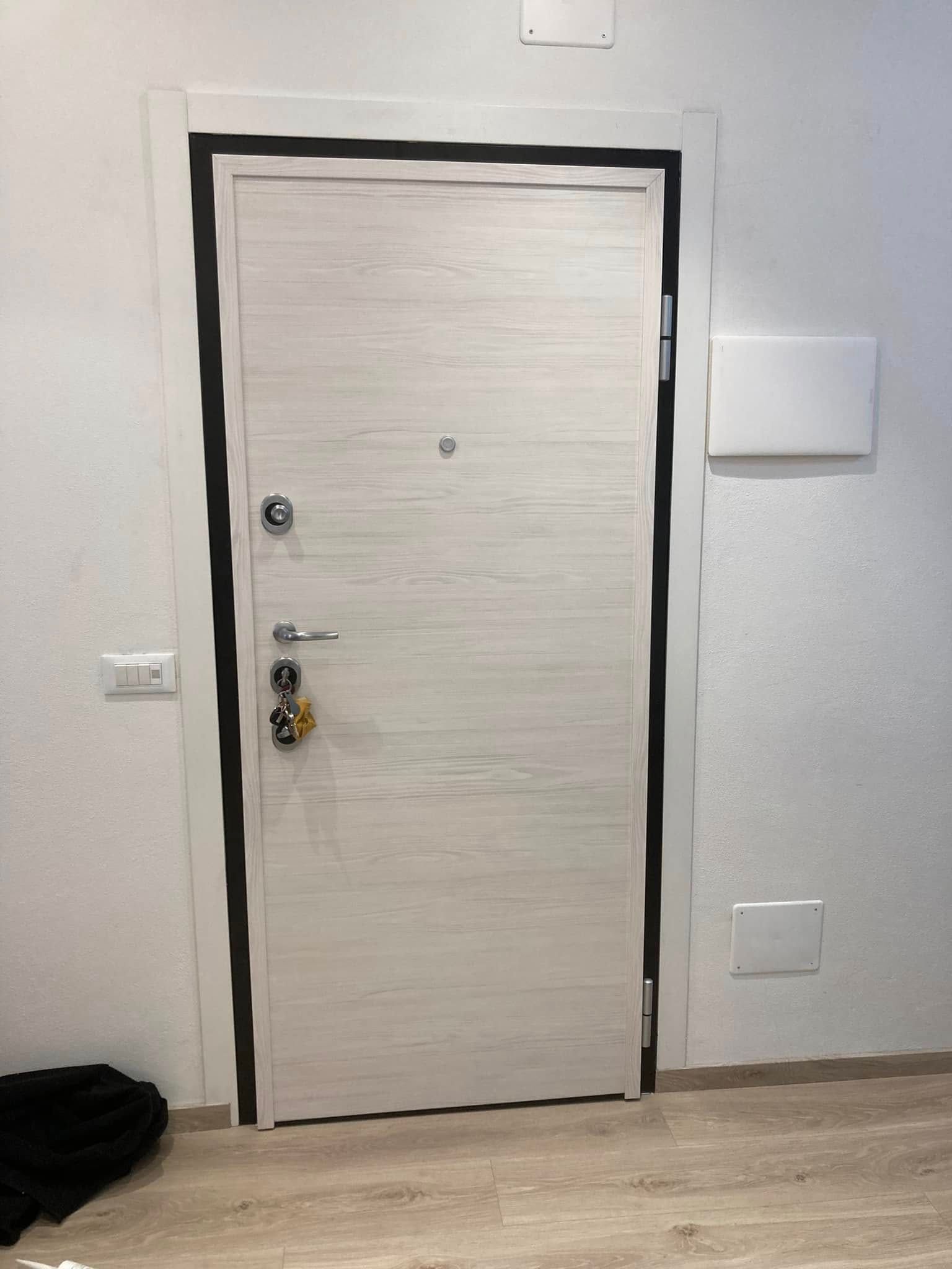 Una porta bianca si trova in una stanza accanto a un muro bianco.