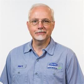 Man in blue work shirt, glasses, smiling, with nametag 