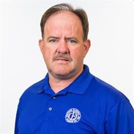 Man with mustache wearing a blue polo shirt, looking at the camera. White background.