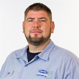 Man in blue uniform with a beard, smiling, looking at the camera.