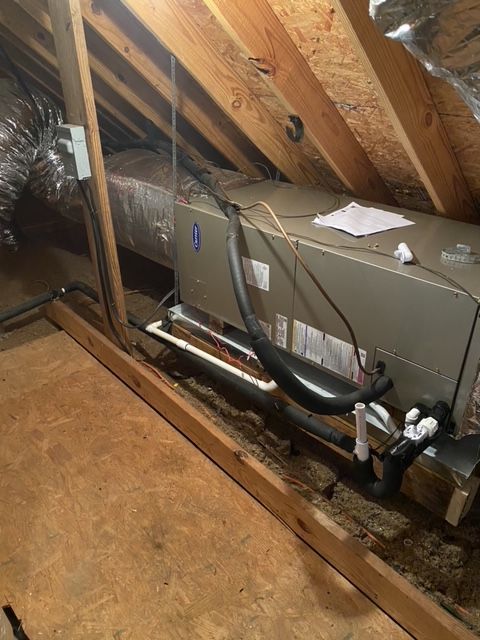 HVAC unit in an attic with ductwork, piping, and electrical components.