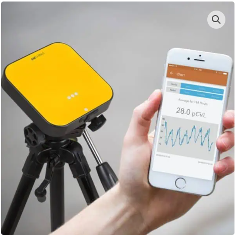 Person using an infrared thermometer on a large, teal engine in an industrial setting.