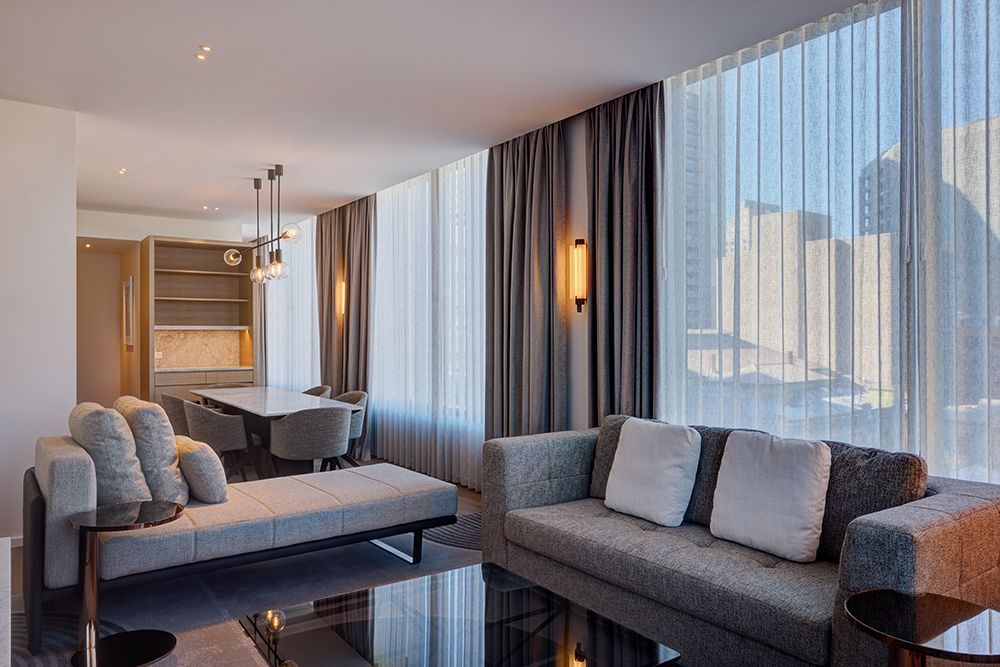 Living room with fireplace, gray furniture, floral centerpiece, and circular mirror.