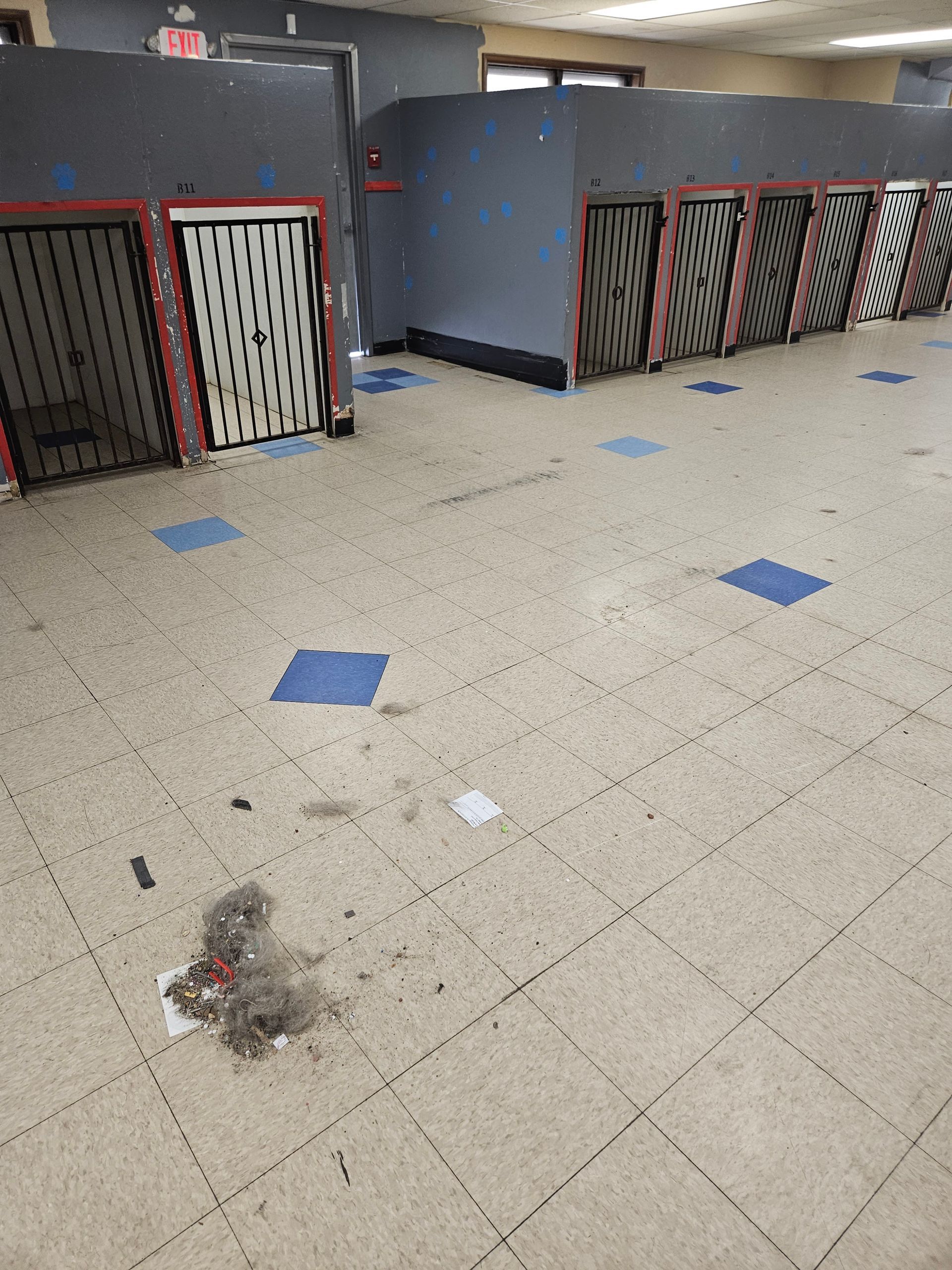 A room with a lot of lockers and a dirty floor.