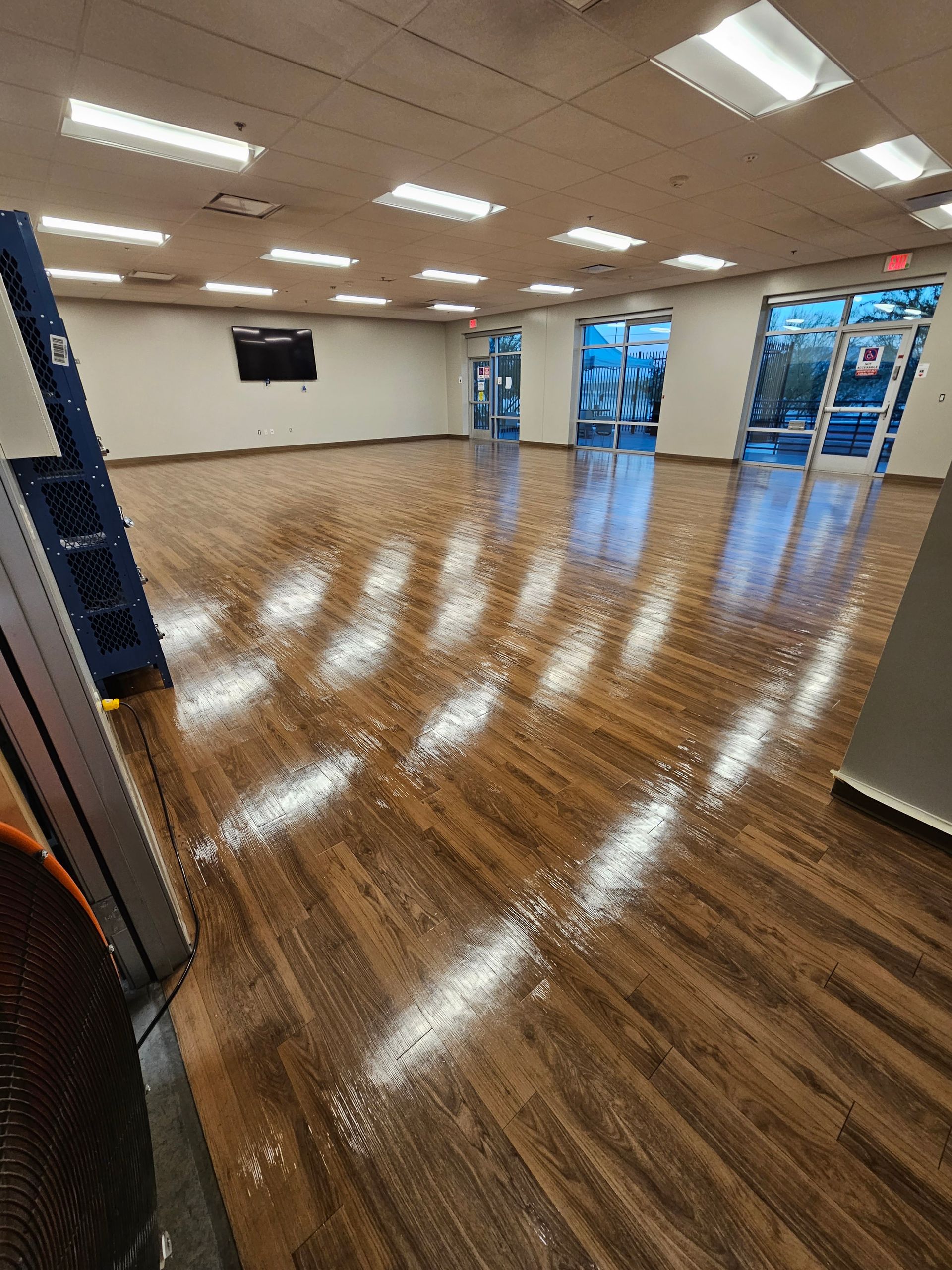 A large room with a wooden floor and a lot of windows.