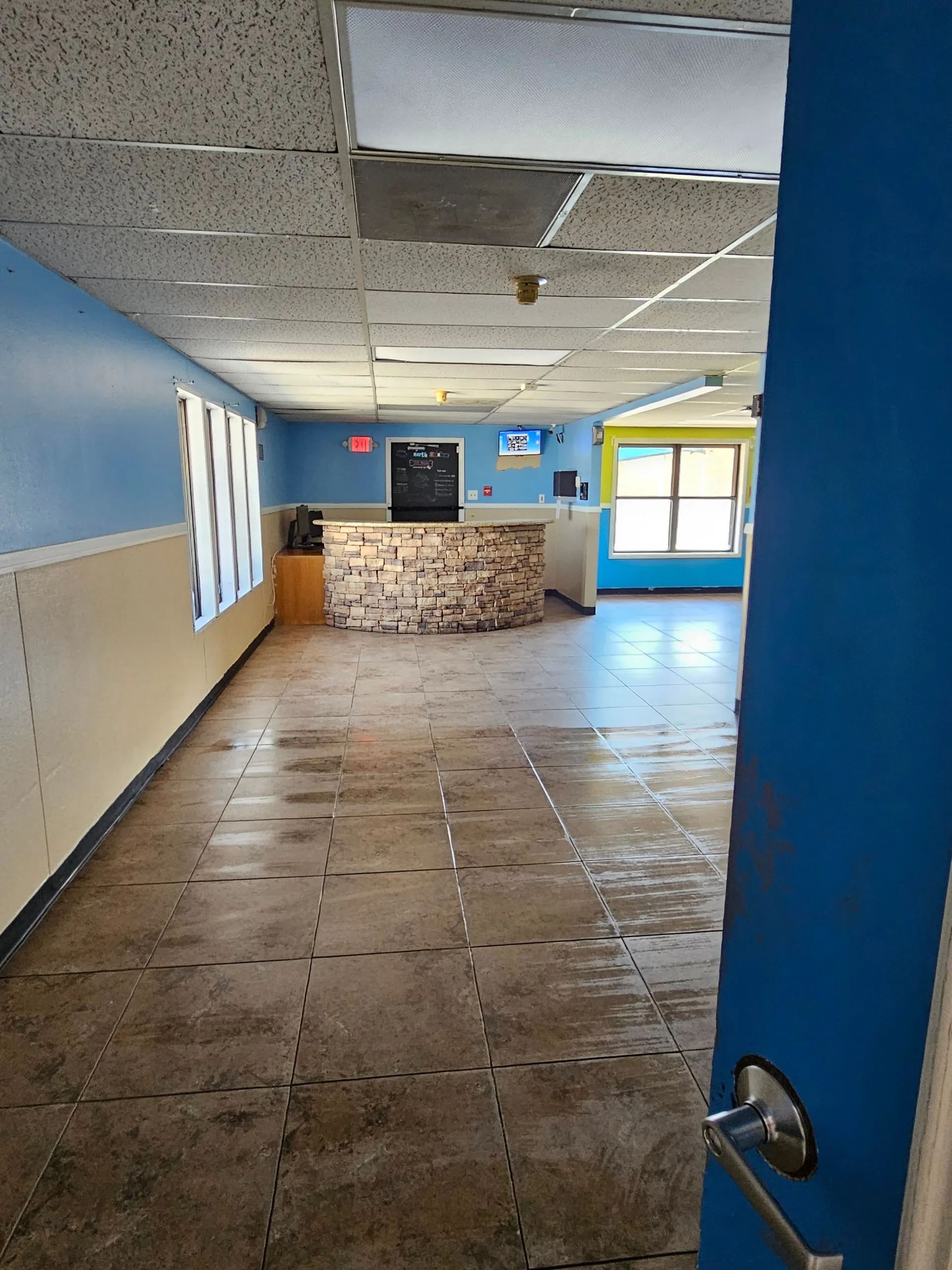 Empty office interior with worn flooring, blue and yellow walls, and a reception desk.