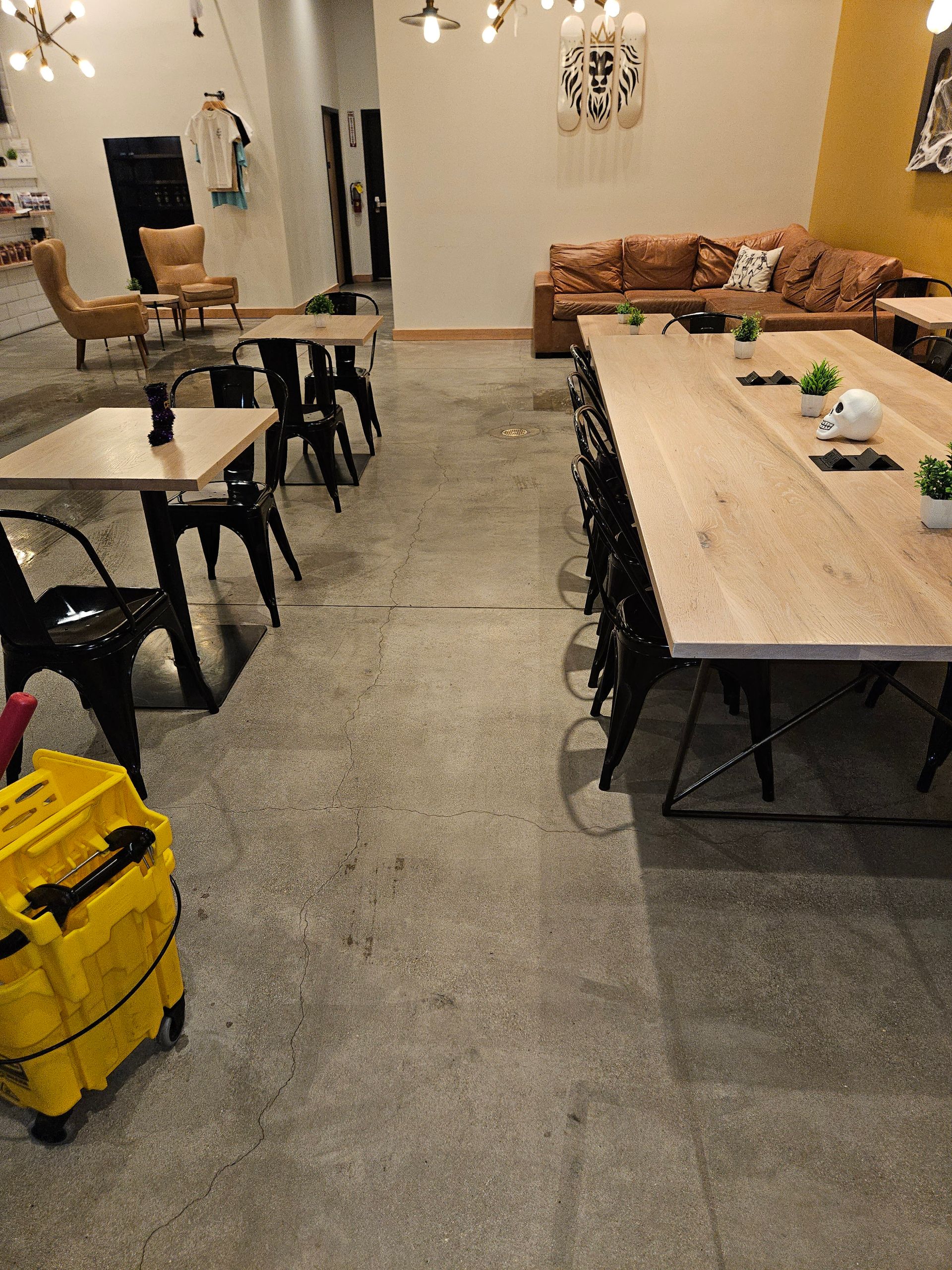 A large room with tables and chairs and a yellow vacuum cleaner.