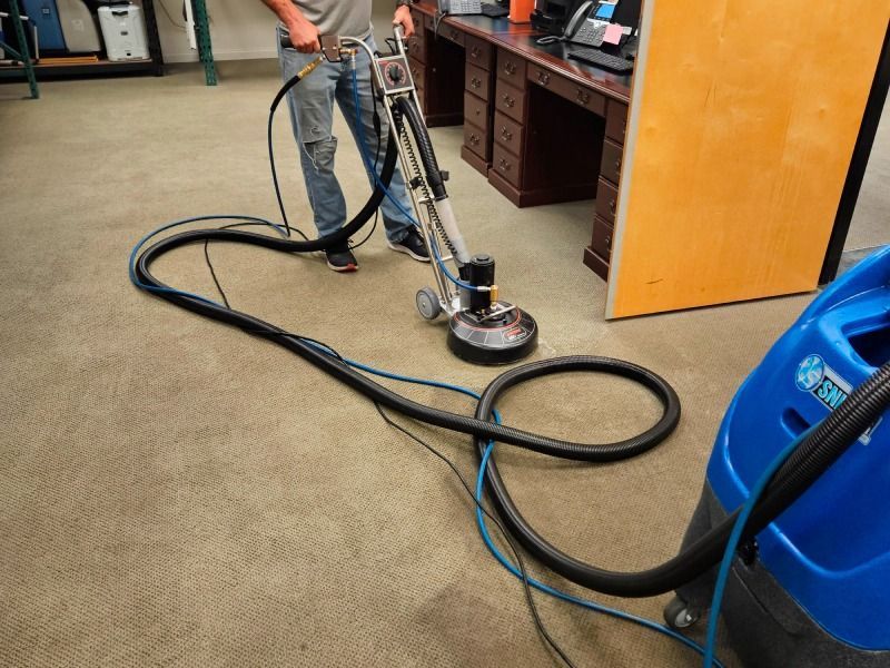 A man is cleaning a carpet with a vacuum cleaner.