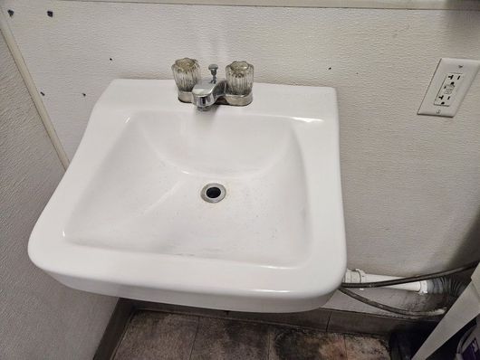 A white sink is hanging on a wall in a bathroom.