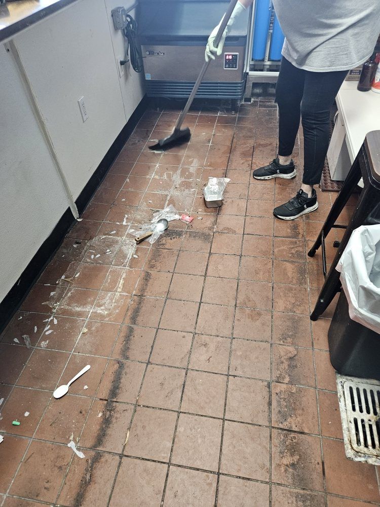 A person is cleaning the floor of a kitchen with a mop.
