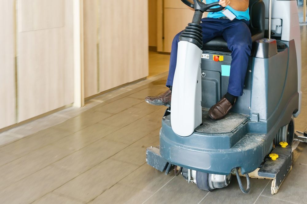 A man is riding a cleaning machine on a tiled floor.