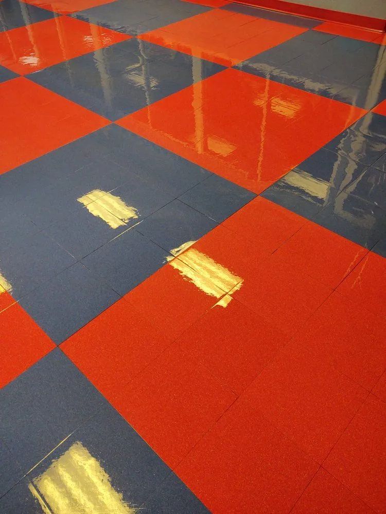 Red and gray checkerboard floor with glossy reflections and yellow tape marks