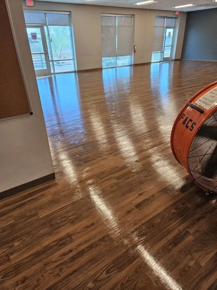 Empty polished office room with wood floors, windows, and a large orange floor buffer on the right