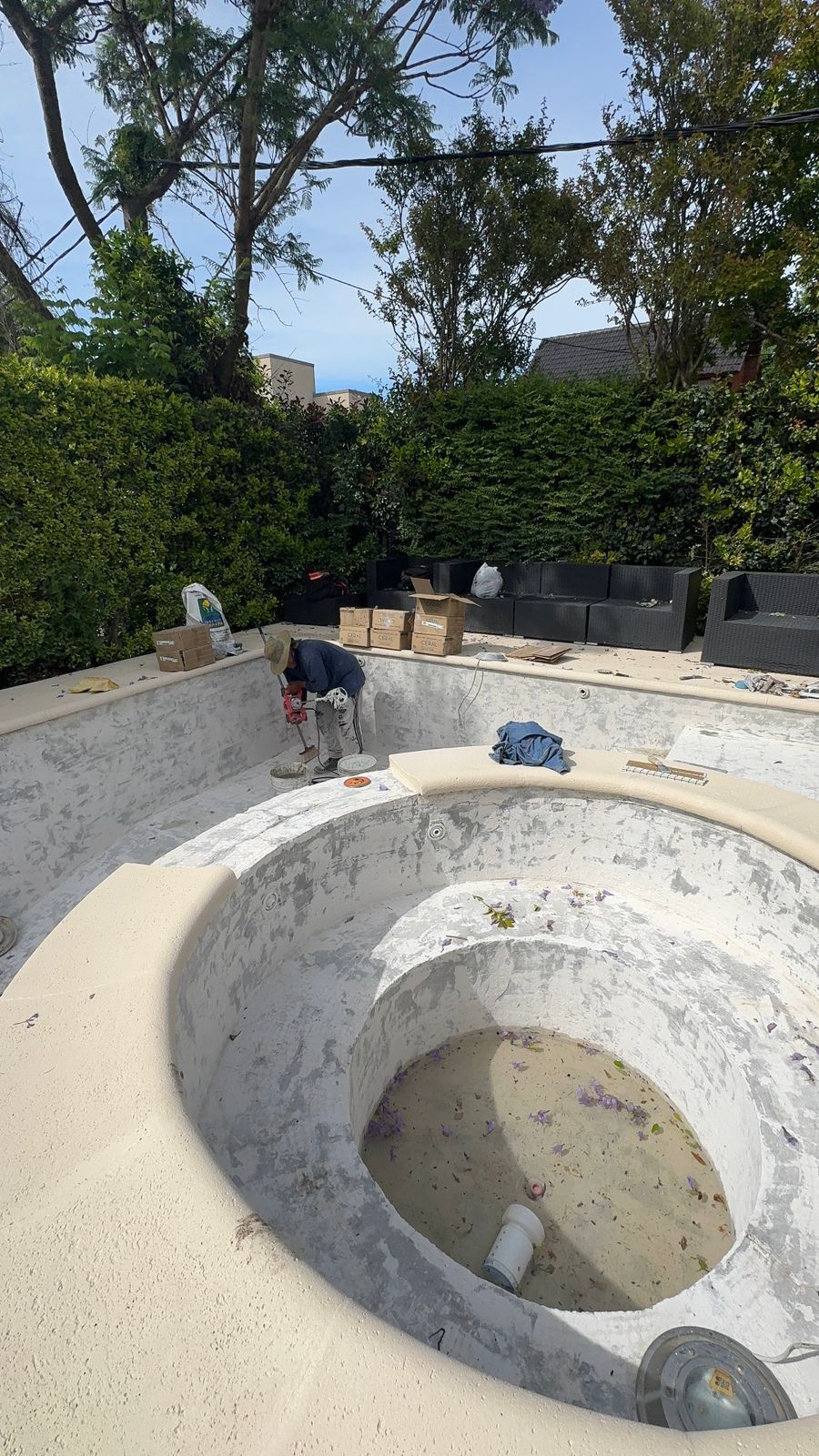 Piscina vacía en la que se trabaja al aire libre con herramientas y escombros.